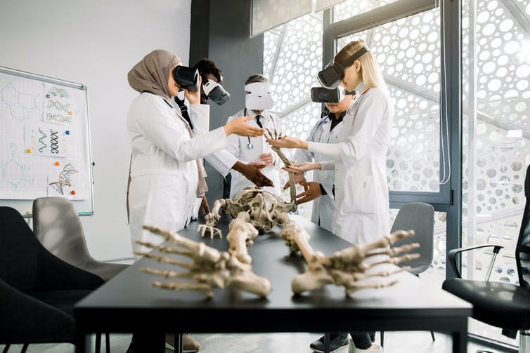 Group of students and professor wearing VR headsets studying skeleton